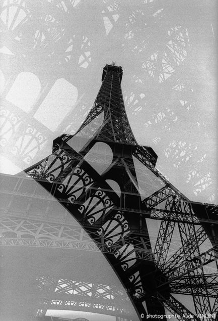 Photographie d’auteur argentique noir et blanc extraite de la série « Paris, Paris, Paris, la ville lumière sans cliché » de la photographe française et parisienne Aude VINCENT.La Tour Eiffel à Paris.
